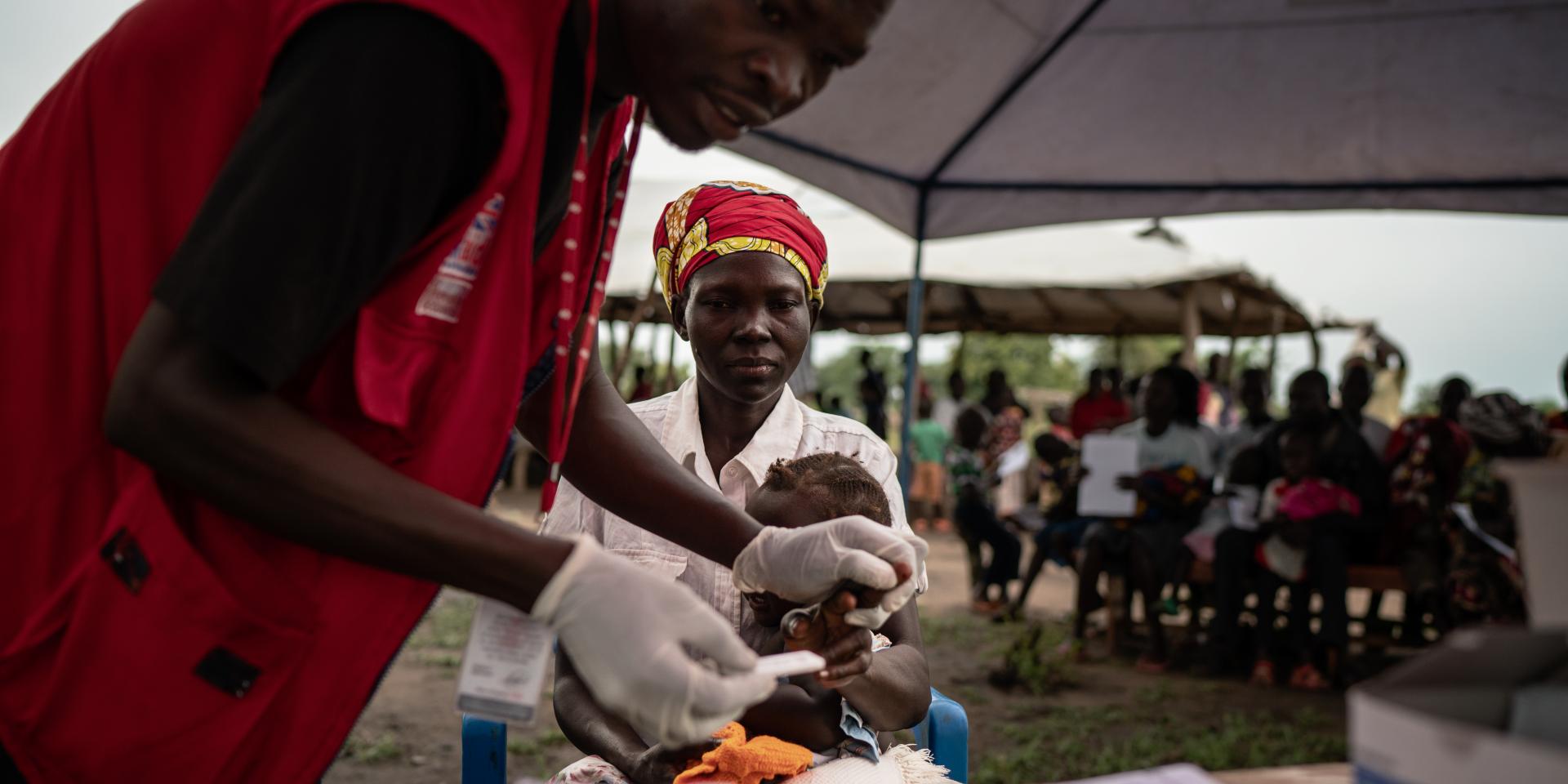 Operatore effettua il test per la malaria su una bimba alla clinica mobile di Save the Children nel campo rifugiati di Mpevi, in Uganda