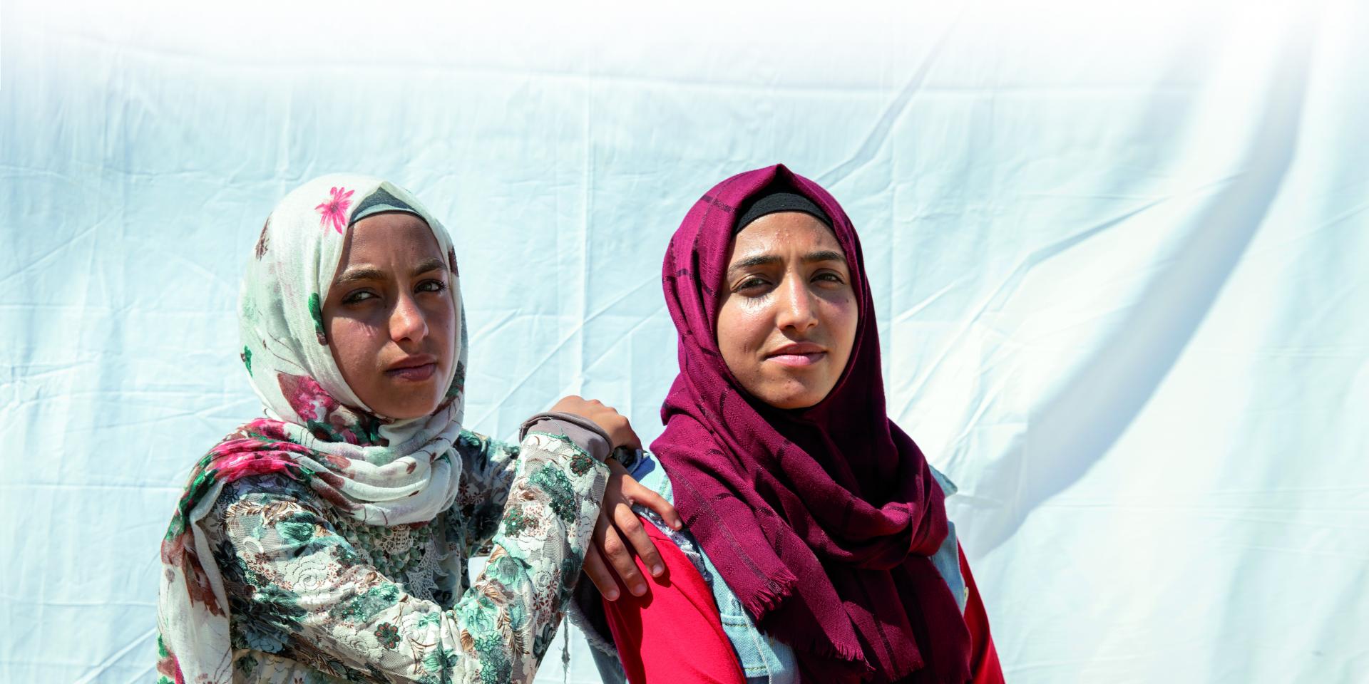 Due ragazze guardano fiere l'obiettivo in un campo profughi siriano in Giordania