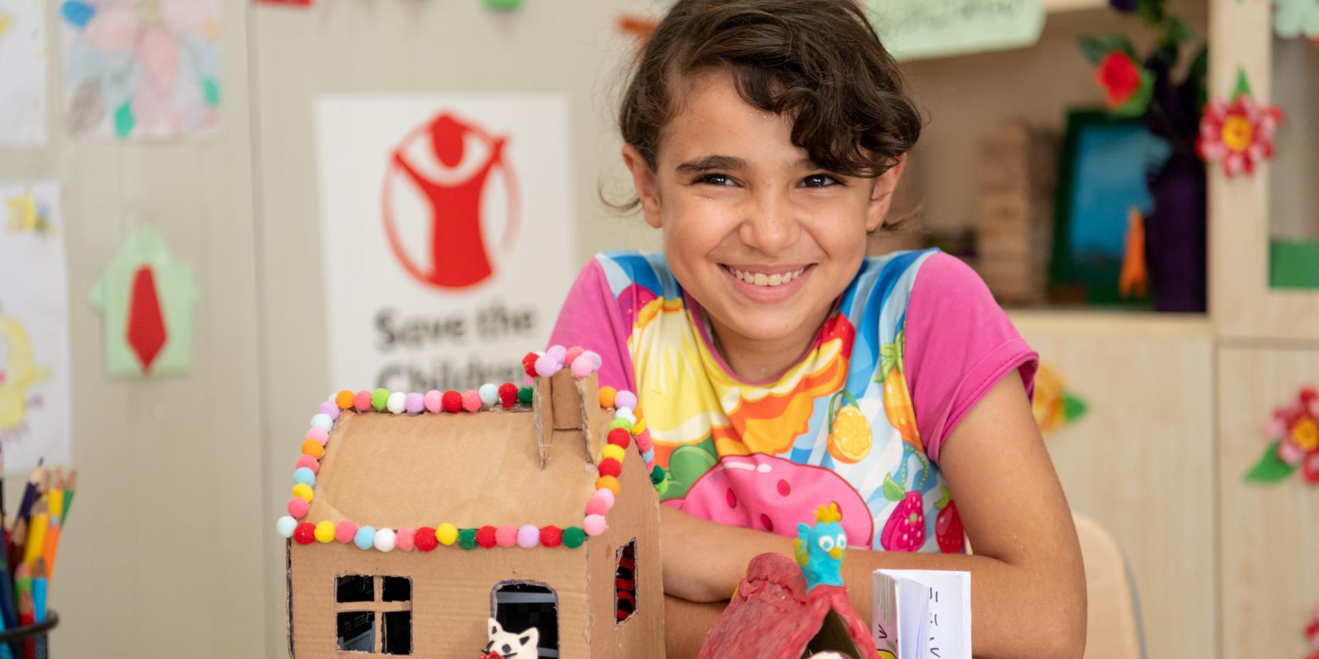Naima, 12 anni, mostra fiera il suo lavoretto (una casetta di cartone) realizzato in un centro educativo di Save the Children in un campo rifugiati siriani nel nord dell'Iraq.