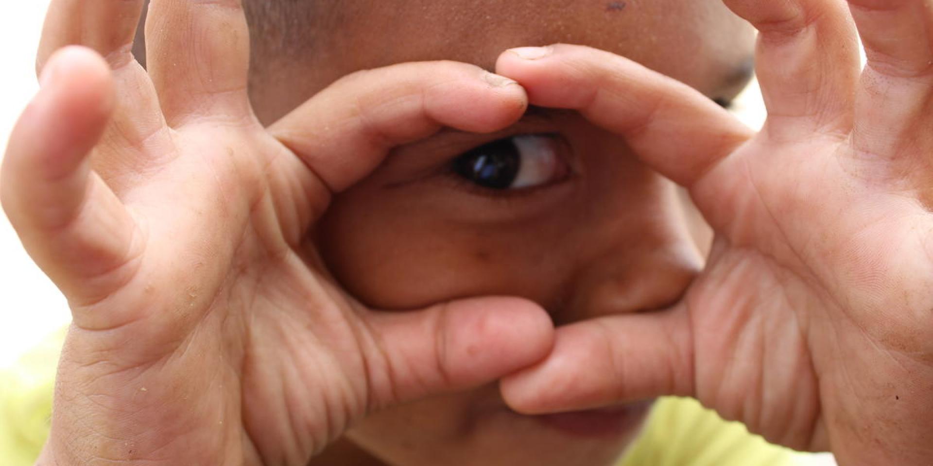 Un bambino gioca sereno in un Child Friendly Space di Save the Children, divertendosi a guardare l'obiettivo di un fotografo