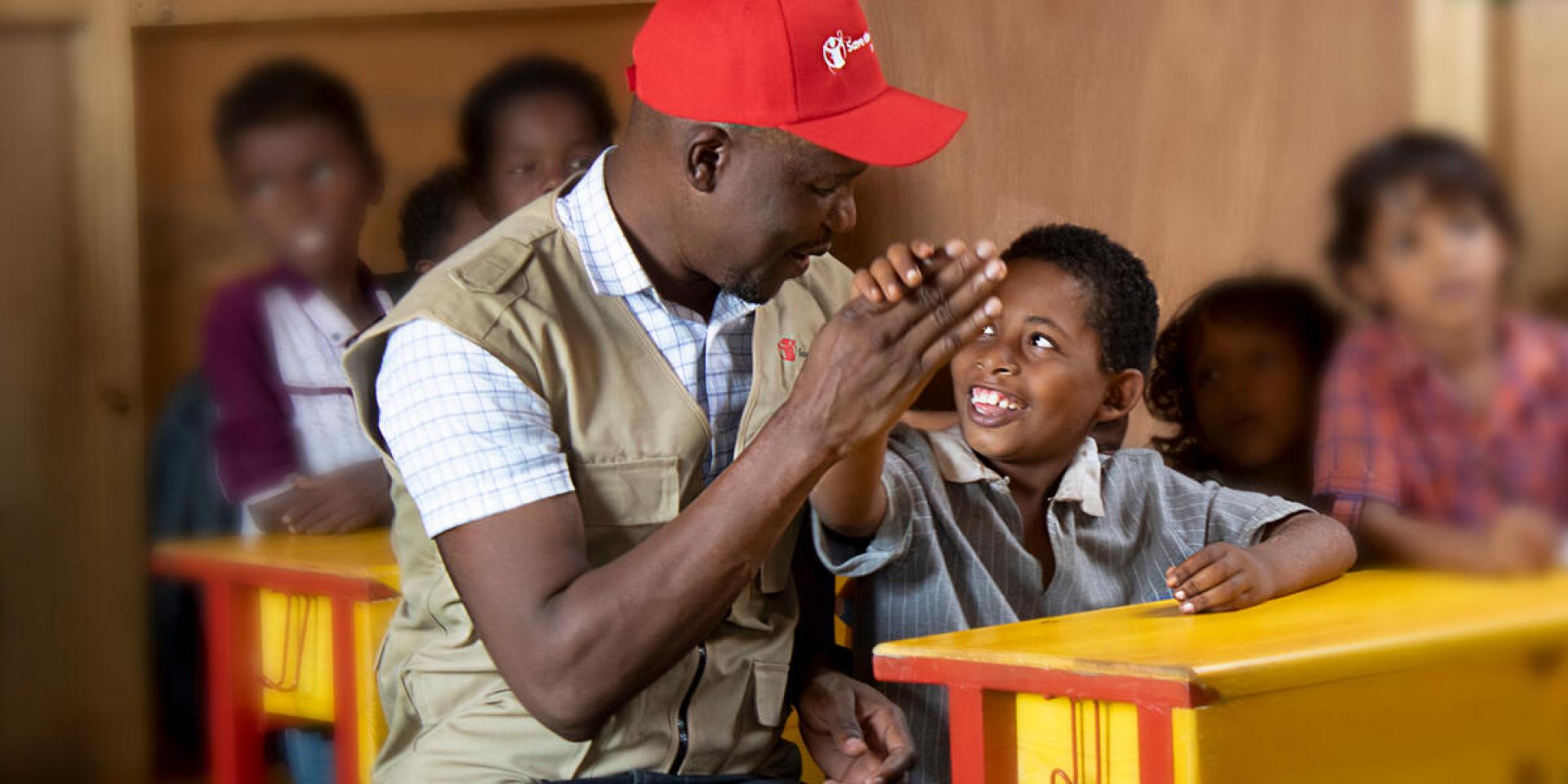 Moses, un nostro operatore, gioca con un bambino in una scuola supportata da Save the Children in Yemen