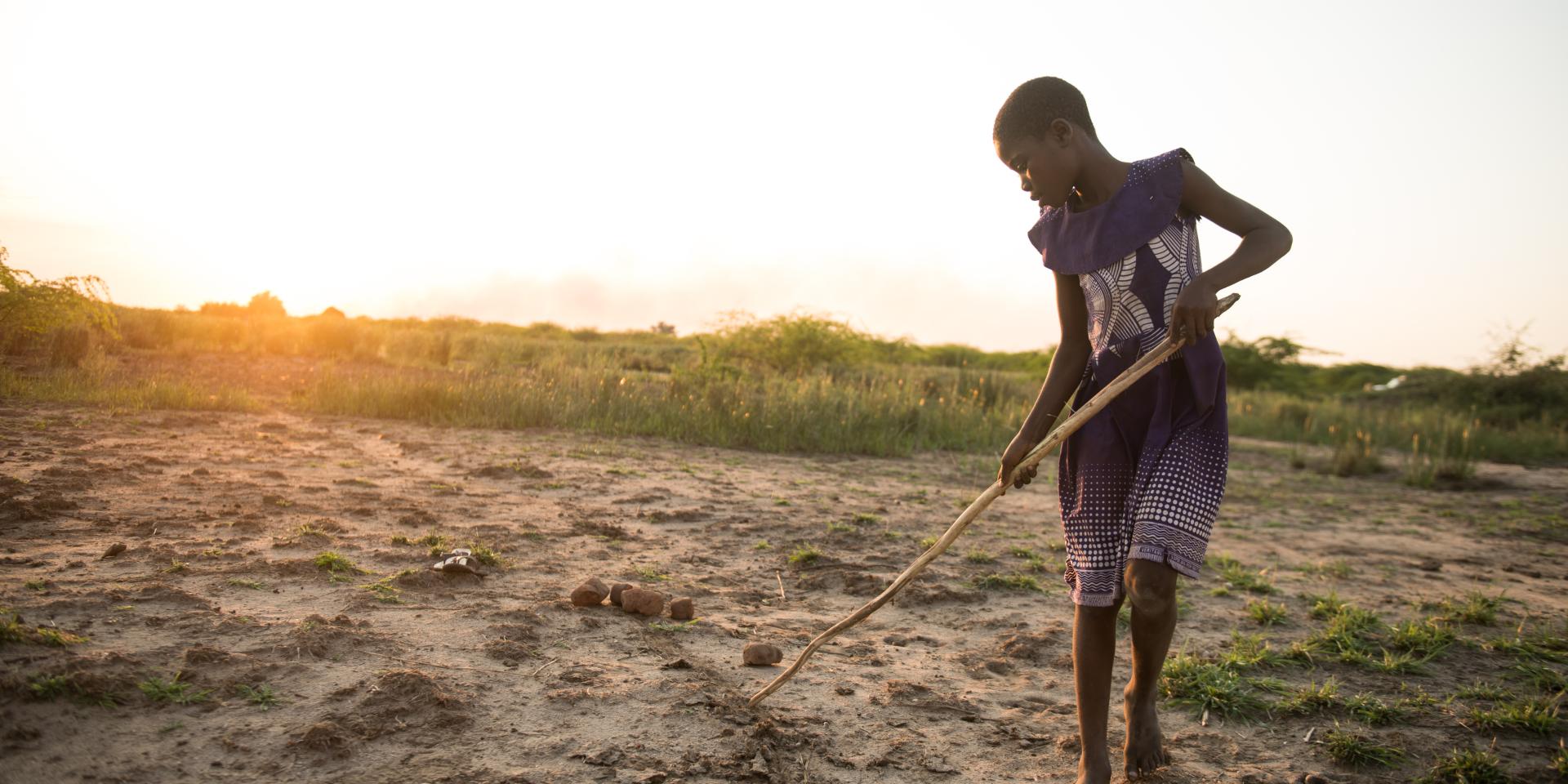 Sarah, 11 anni, disegna su un terreno prosciugato dopo un’alluvione in Malawi