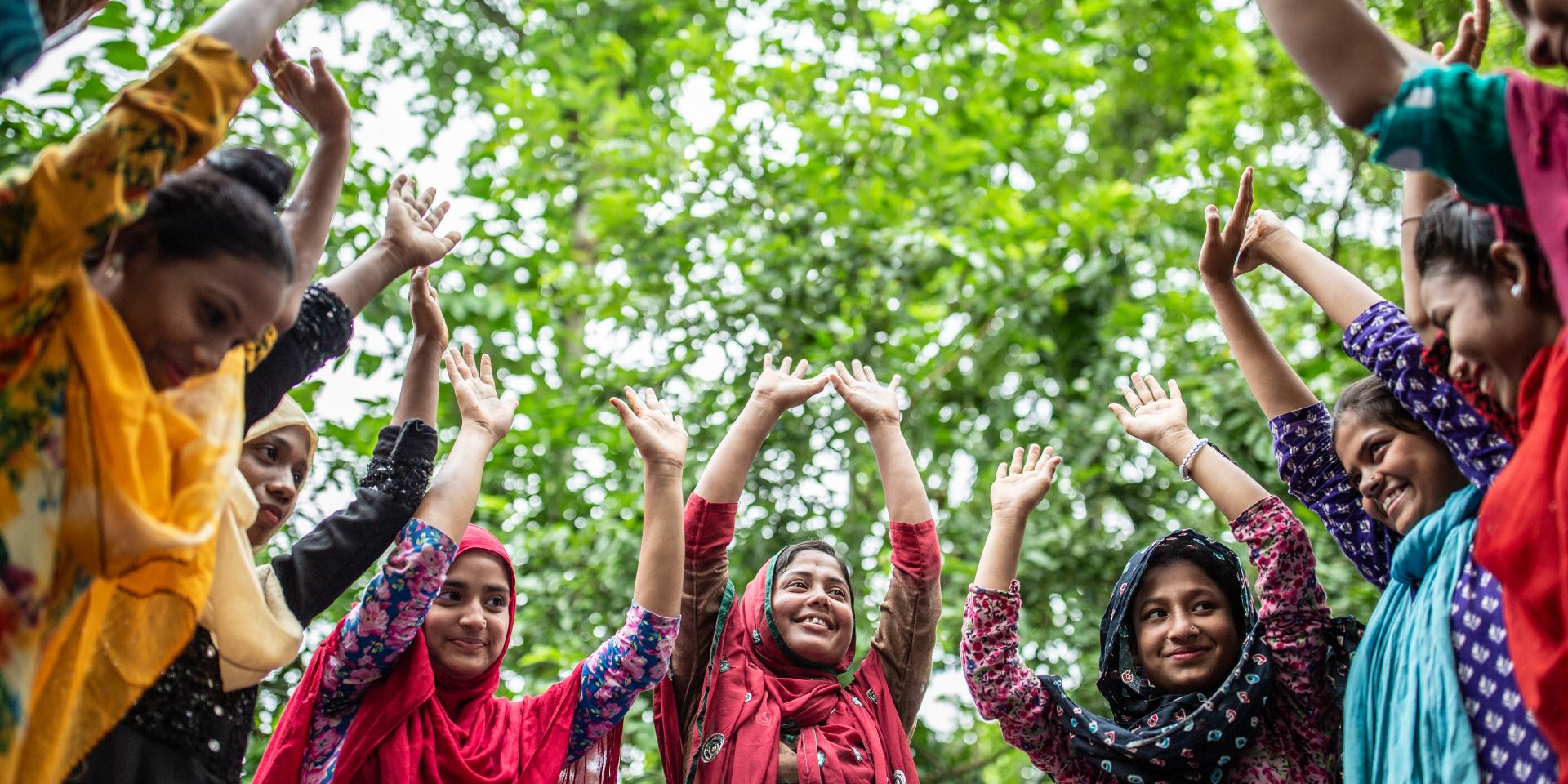 Un gruppo di ragazze in Bangladesh si riuniscono in cerchio con le mani alzate per motivarsi e supportarsi nelle attività che svolgono per contrastare i matrimoni precoci.