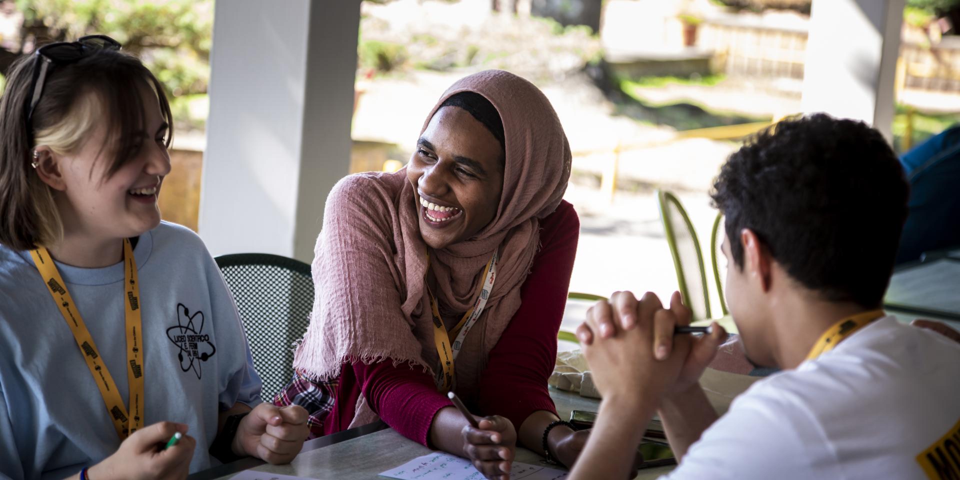 Due ragazze e un ragazzo ridono durante un’attività di gruppo realizzata all’interno del Summer Camp 2023 del Movimento Giovani.