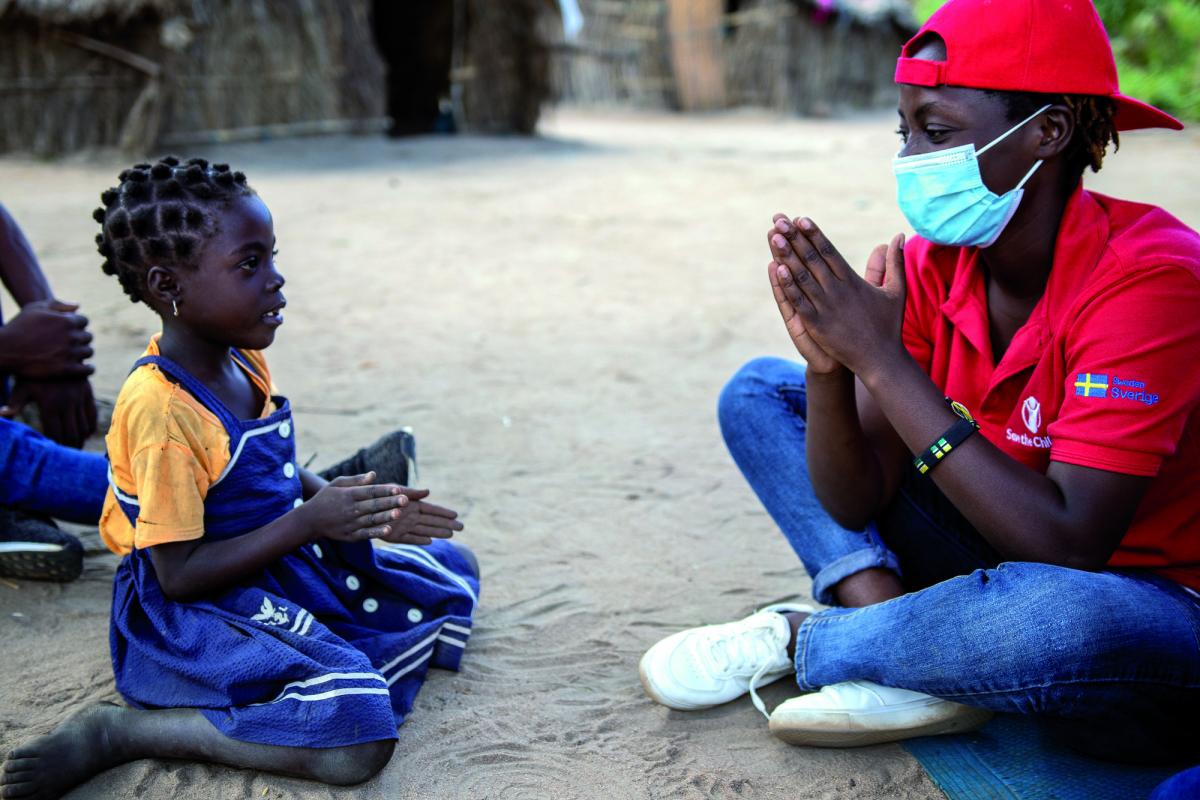 Una bimba gioca seduta in terra con un'operatrice di save The Children in un campo profughi a Cabo Delgrado, Mozambico