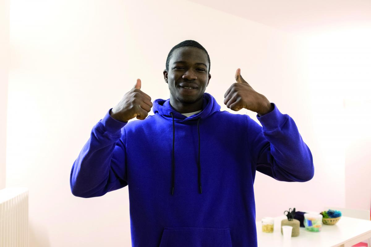 Precious, ragazzo nigeriano di 22 anni, mentre sorride alla fotocamera alzando in alto entrambi i pollici