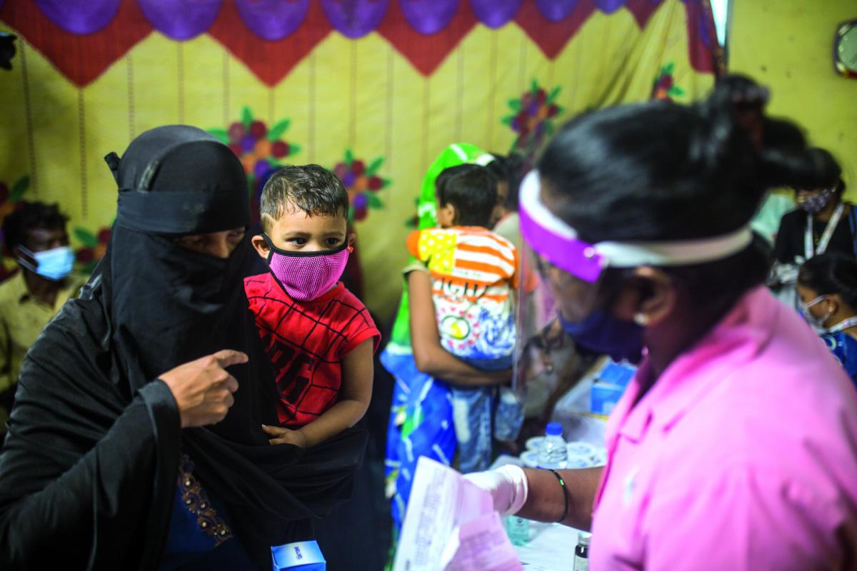 Una madre con in braccio il proprio bimbo, durante una visita di controllo, per eventuali segni di malnutrizione, effettuata dagli operatori di Save The Children a Mumbai, India
