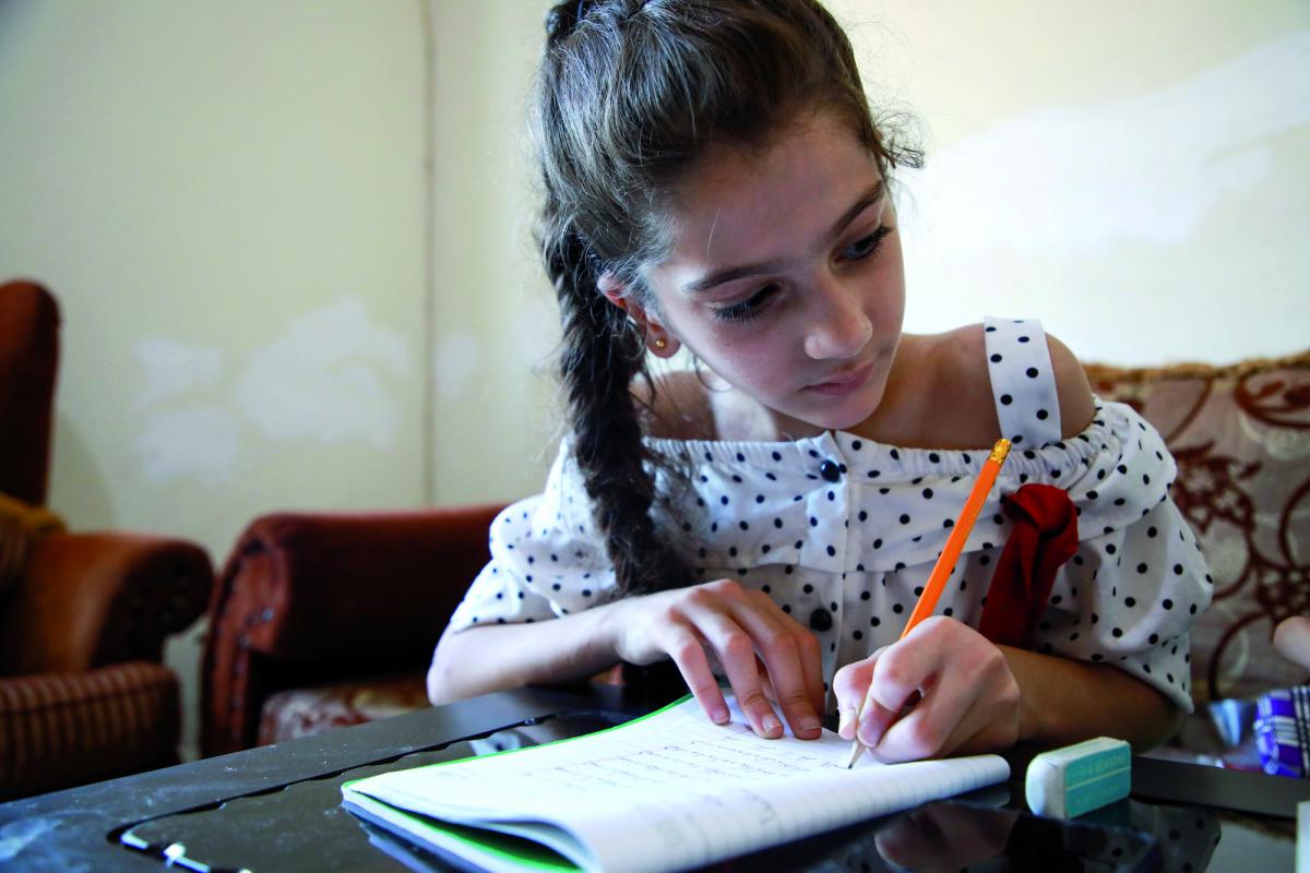 Bimba libanese che scrive su di un quaderno nella sua classe a Tripoli