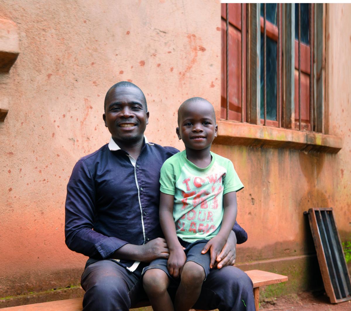 Bimbo del Mozambico sorridente mentre è seduto sulle gambe del padre