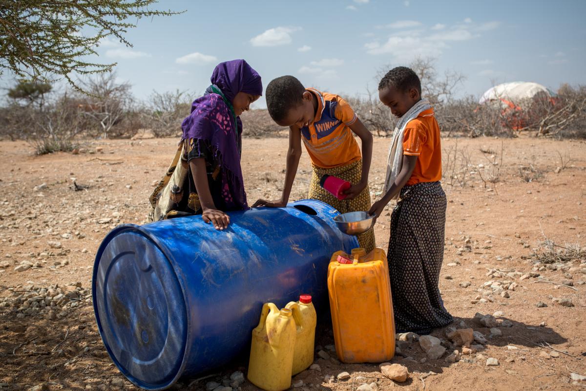Tre bambini raccolgono acqua da un contenitore in Somalia