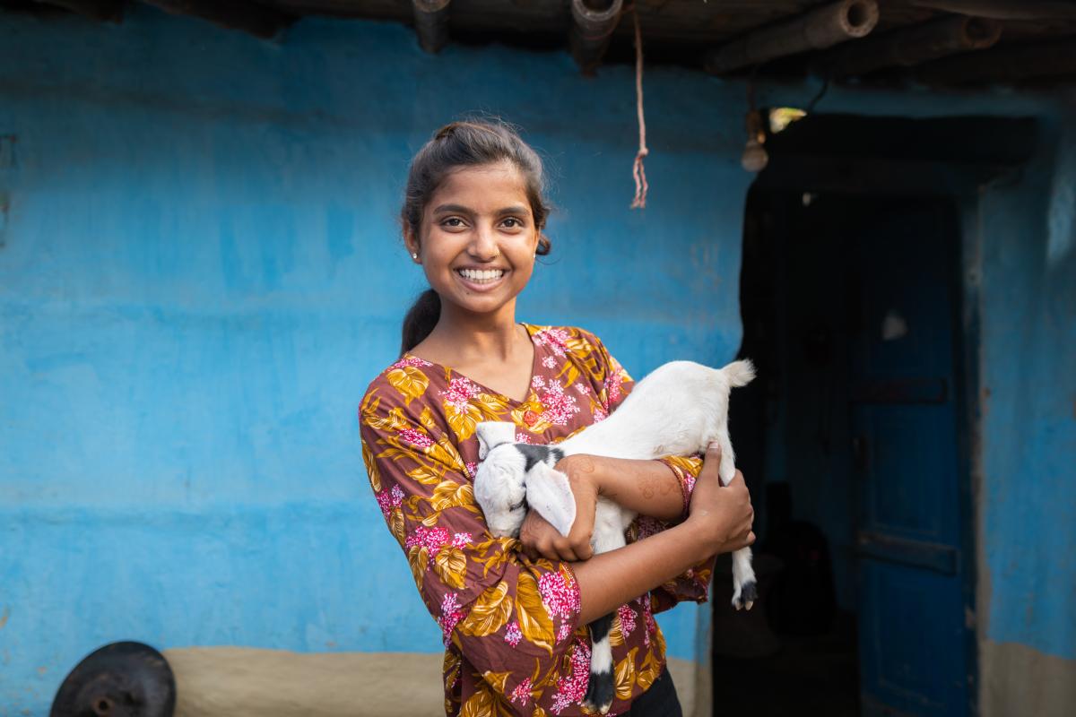 Una ragazza sorridente tiene in braccio un agnellino