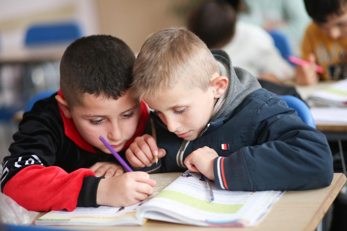 Due bambini a scuola leggono insieme sullo stesso libro di testo