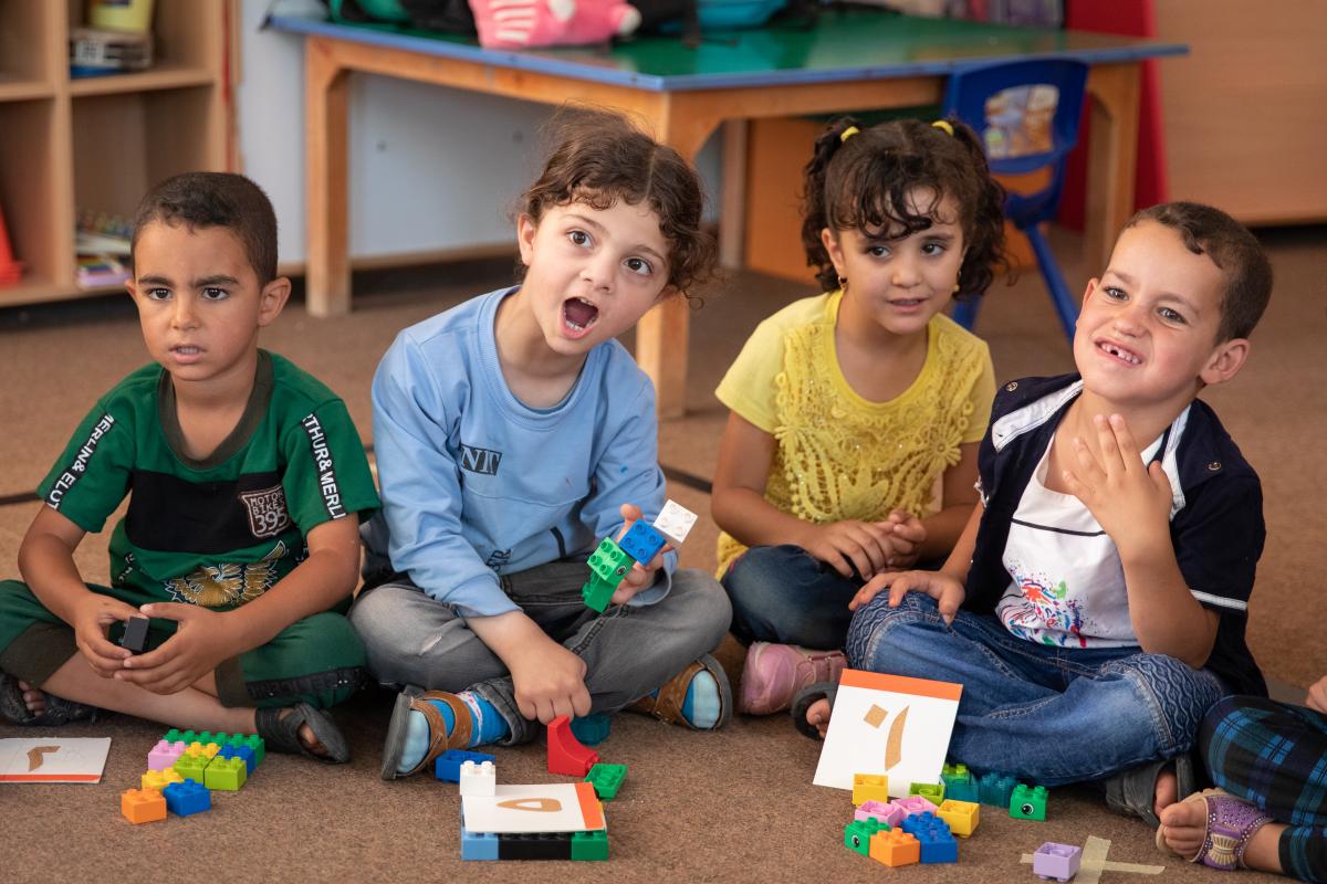 Bambini seduti in una scuola giocano con delle costruzioni