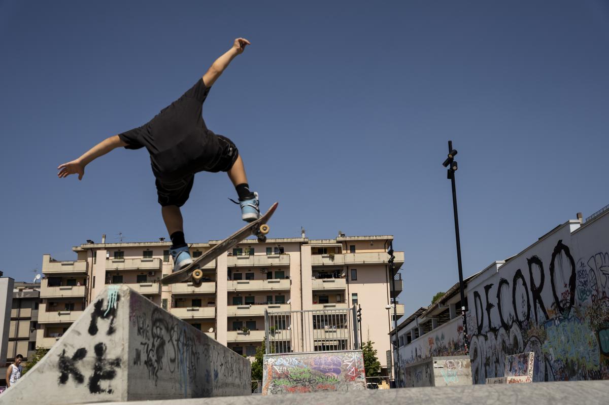 Un ragazzo salta in aria con il suo skateboard all'interno dello skate park di Ostia