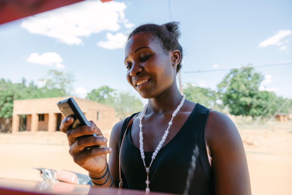 Una donna del Malawi digita sul suo telefono cellulare.